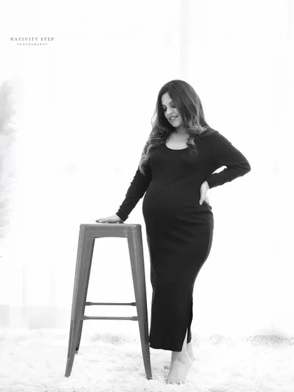 A simple and elegant black and white portrait. The high-key lighting and minimalist setting put all the focus on the mother-to-be and her beautiful silhouette.