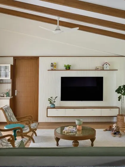 The family space in 'House of Kismish' has a true cottage charm, with a sloped roof and exposed wooden rafters. The floating TV unit and integrated pantry make it both cozy and functional.