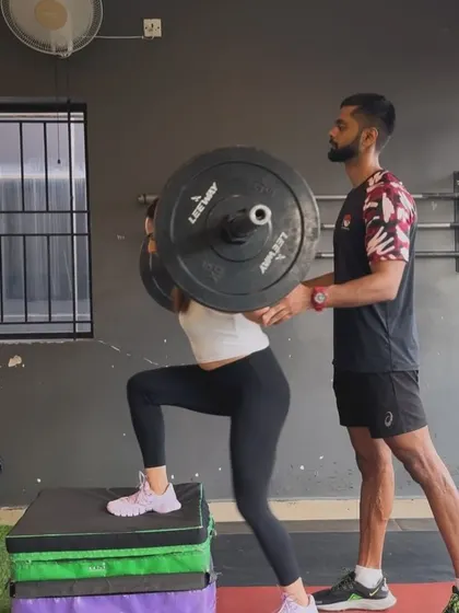 A client performs a weighted step-up, an excellent unilateral exercise for building leg strength and improving balance. I am closely supervising to ensure perfect form and safety.