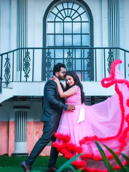 A beautiful shot of a couple in a flowing pink gown and a dark suit, capturing a romantic moment in front of a stately building.