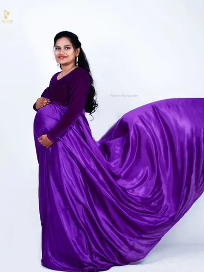 Creating a "flying gown" effect with the purple satin skirt adds a touch of magic and drama to this studio maternity shot.