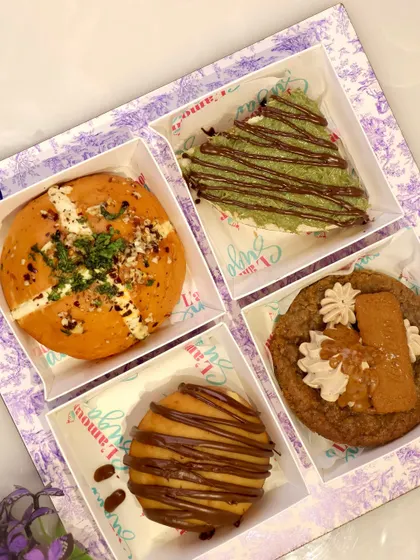 A top down view of our assorted Rakhi box, featuring a Korean bun, kunafa cheesecake, Biscoff cookie, and a bombolini.