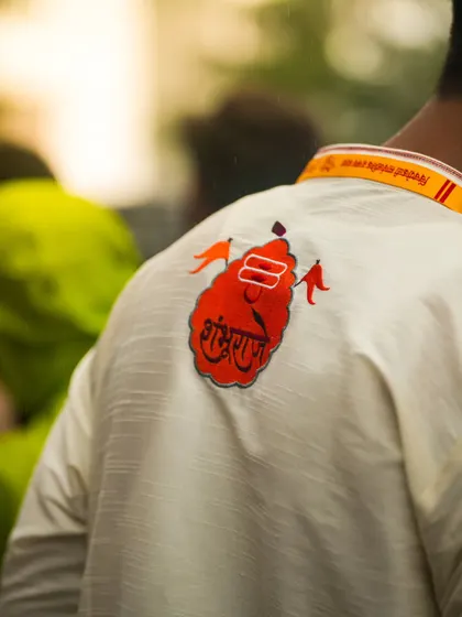 A detail shot focusing on the back of a devotee's kurta, which has a custom patch for the festival. It's these small details that tell the larger story of community and celebration.