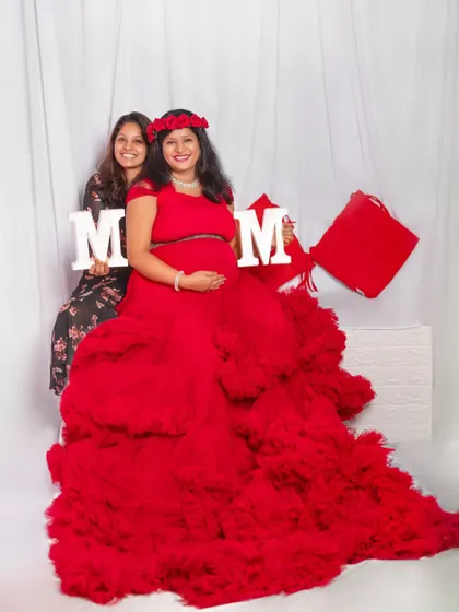 Make your maternity shoot even more special by including a loved one. Here, the mom-to-be is holding 'MOM' props in our popular red ruffle gown.