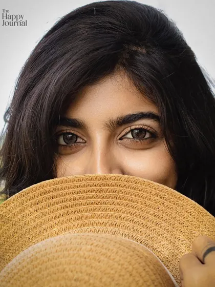 A playful and engaging close-up shot from an outdoor branding session. Using a prop like a hat can help bring out a subject's personality and create a sense of mystery and charm.