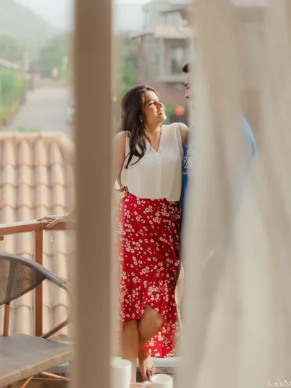 An artistic shot through a window curtain, capturing a candid moment of the couple sharing a laugh on their balcony.