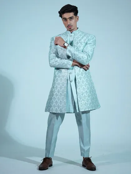 A full-length shot of the light blue Indo-western sherwani. The slim-fit pants and long jacket create a modern, elegant silhouette.