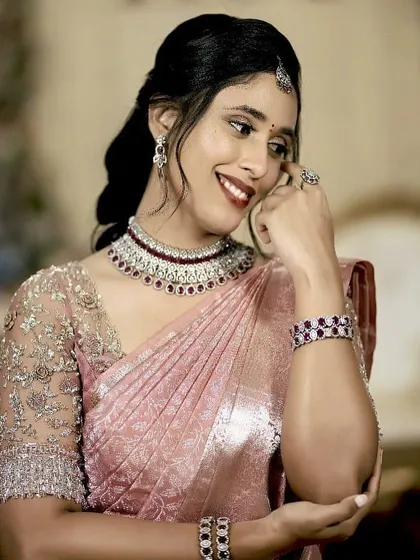 This bride looks radiant in her pastel pink saree. The custom blouse with intricate silver embroidery adds a touch of glamour to her engagement look.