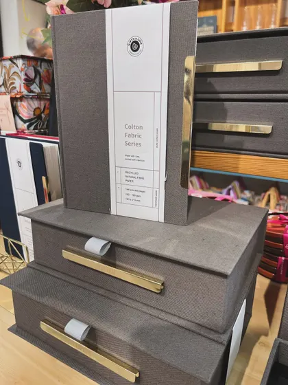 A stack of our Colton Fabric series keepsake boxes and a matching notebook. The design is minimal, allowing the quality of the materials to shine through.