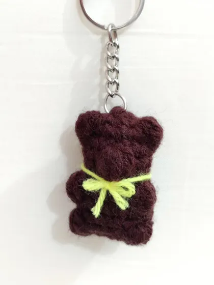 A brown gummy bear keychain with a yellow bow.