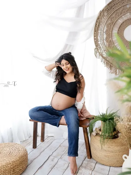 A relaxed and casual portrait in a boho setting. The mom-to-be's comfortable jeans and crop top create a modern and authentic look.