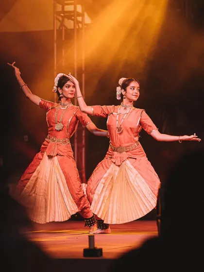 Two classical dancers perform in perfect unison, their forms illuminated by a warm spotlight. This image highlights the symmetry and grace of their art form.