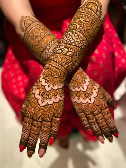 This back-of-hand design features a mix of traditional motifs and modern patterns. The red nail polish provides a beautiful contrast to the dark henna.