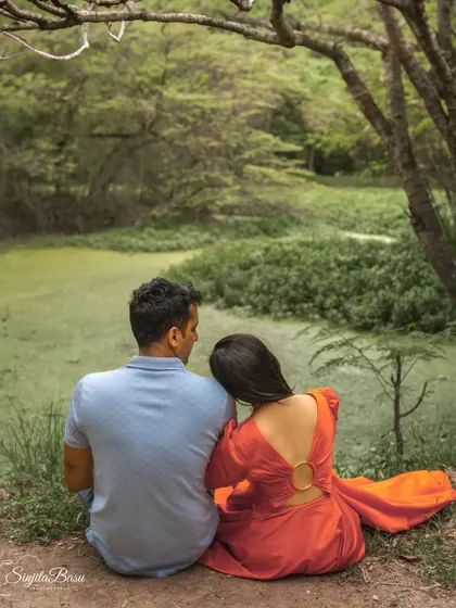 A duplicate of ID 35, this shot from behind captures a couple's closeness and the tranquility of their natural setting as they sit by a green pond.