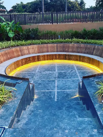 The steps leading down into the sunken lounge are made of dark stone, contrasting with the warm wood of the bench.