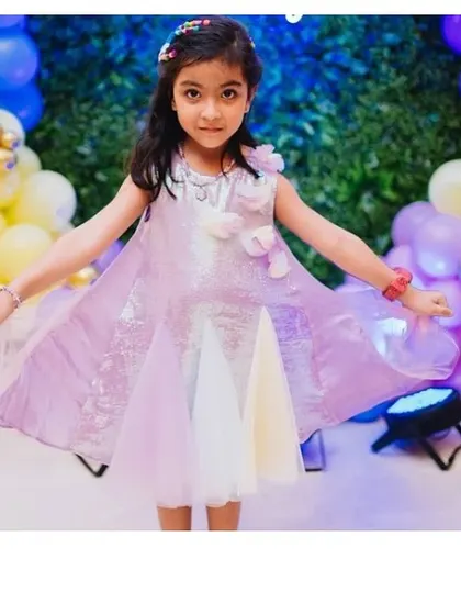 A happy client wearing her purple "Pari" dress. The iridescent sequins and pastel tulle panels catch the light beautifully as she moves.