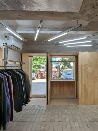 The entrance portal, framed in natural wood, acts as a warm transition from the street into the main retail area. The view shows the interplay of different materials and the open, flexible layout.