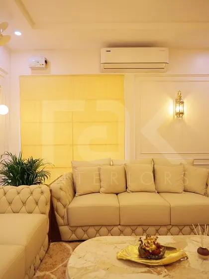 A full view of a classic and luxurious living room. The combination of tufted sofas, wall paneling, and warm ambient lighting from wall sconces creates a timeless and sophisticated look.