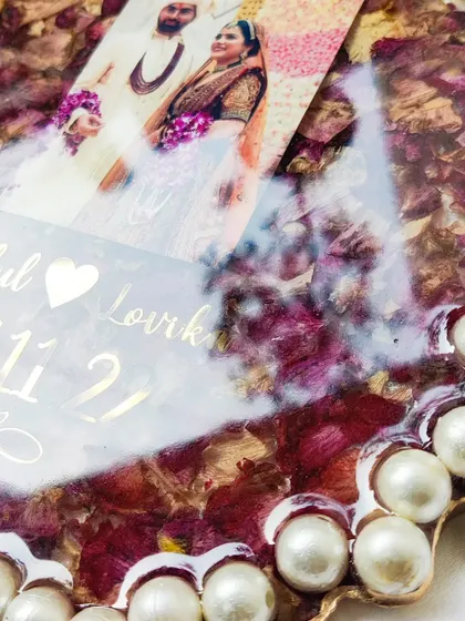 A close-up view of the intricate details in a varmala preservation frame. You can see the texture of the petals and the shine of the gold lettering, all sealed under a glossy resin finish.