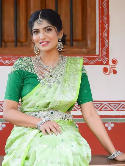 A model styled in a light green saree with a full silver-finish diamond and emerald look-alike bridal set.