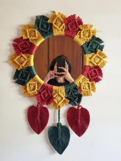 Adding a touch of artisanal flair to your walls with this stunning multicolored macrame mirror. The vibrant colors and hanging leaves make it a playful and unique piece.