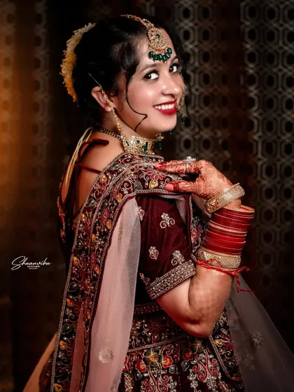 A smiling, over-the-shoulder pose from the bride, showing off the beautiful back design of her blouse and her happy expression.