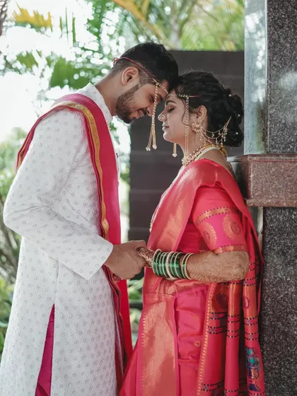 An intimate portrait of a Maharashtrian couple. The bride's makeup is soft and romantic, with a focus on glowing skin and defined eyes, perfectly complementing her pink saree.