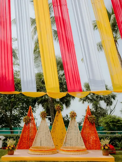 A closer look at the unique seating arrangement for a Haldi ceremony. The cone-shaped backdrops are meticulously crafted from strings of marigold and jasmine flowers, creating a beautiful and fragrant focal point.