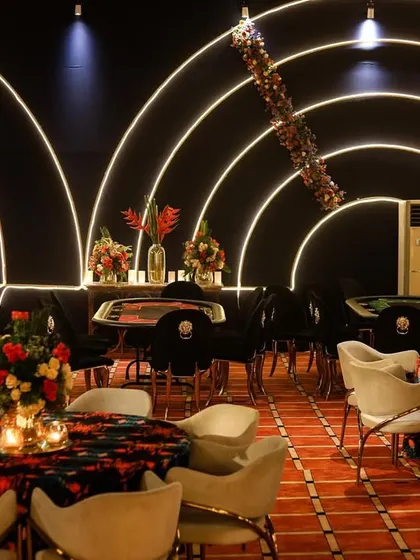 A wider view of the poker area, showing multiple tables set up for a large number of guests to enjoy the games simultaneously.