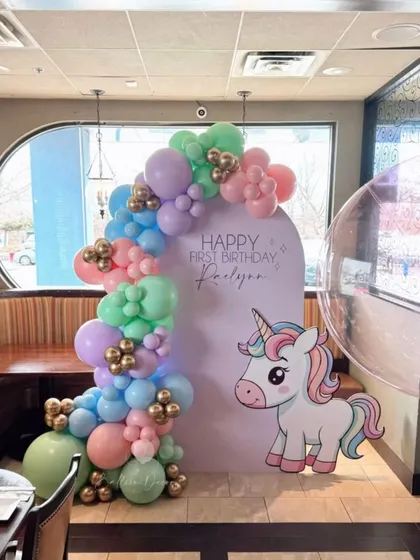 A simple yet charming unicorn theme for a first birthday, with a pastel balloon arch against a custom backdrop and a cute unicorn cutout.