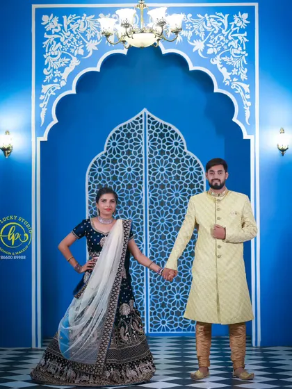Posing against a vibrant blue backdrop, the coordinated outfits truly stand out. I ensure every detail, from the groom's attire to the bride's makeup and dupatta, is perfect.