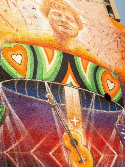 A close-up of the Ed Sheeran mural, focusing on the guitar and the heart motifs. The textured paint and bright colors are clearly visible in this detailed photograph.