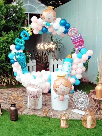 A classic "Boy or Girl" gender reveal party setup. The circular balloon arch incorporates both pink and blue, with fun foil balloons like a baby foot and bottle to add to the theme.
