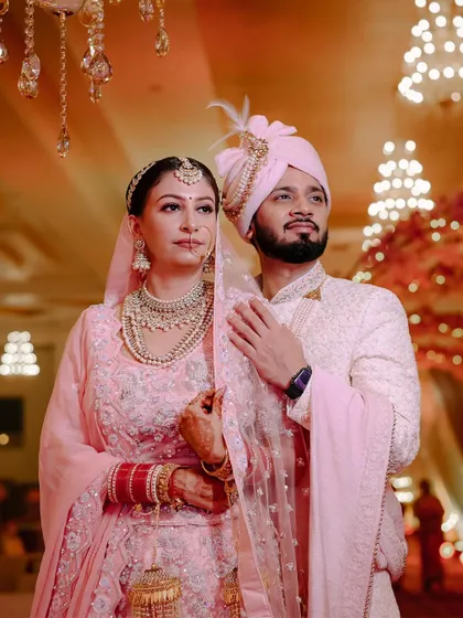 A classic portrait of the couple in their matching pastel pink wedding outfits.