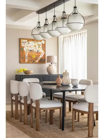 The dining area in Apartment 1600 continues the mid-century modern theme. A statement light fixture hangs over the dining table, while a piece of vibrant art adds personality to the space.