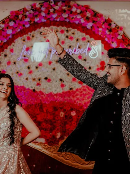 The dance floor is the heart of the Sangeet. We capture the energy of the couple's performance, with a vibrant floral backdrop and custom neon sign adding to the festive atmosphere.
