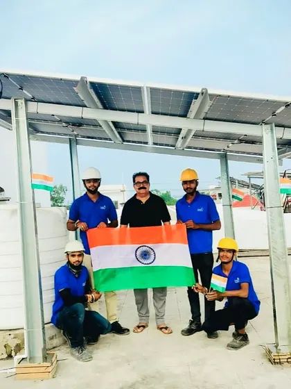 A customer and our full installation crew pose with a large Indian flag under the new solar system.