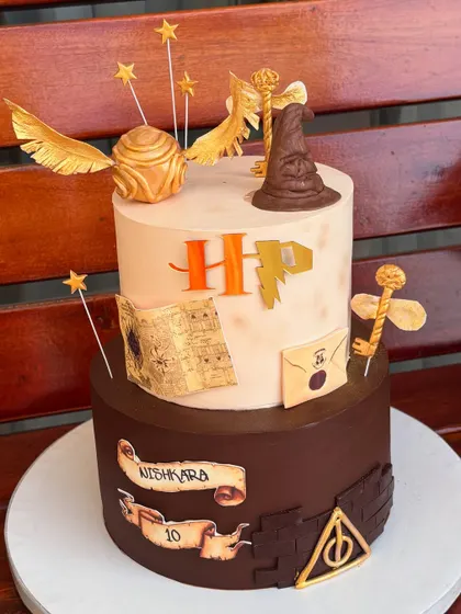 For the ultimate Potterhead, we designed this magical two-tier Harry Potter cake. It's packed with iconic, handmade fondant details like the Sorting Hat, Golden Snitch, and a letter from Hogwarts.