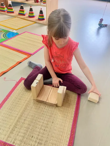 This girl is focused on building a stable structure on her mat. Block play allows children to test their ideas about balance, symmetry, and gravity in a hands-on way.