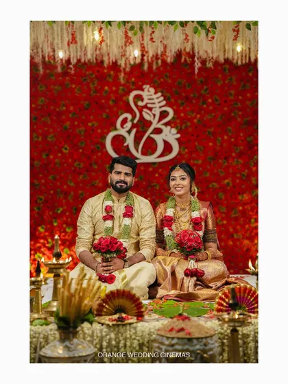 A formal portrait of the couple on their wedding stage, in front of a Ganesha symbol.