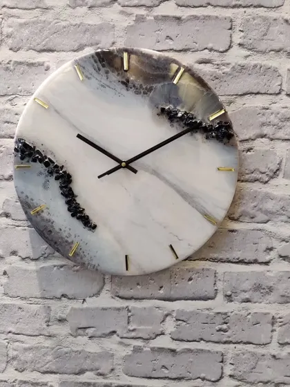 A full view of this 14 inch black, grey, and golden resin clock against a brick wall. The natural stone effect is perfect for modern interiors.