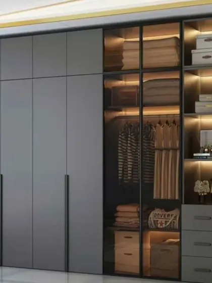A dark and moody wardrobe design in matte grey. The glass section with internal lighting is perfect for showcasing hanging clothes, folded items, and accessories.
