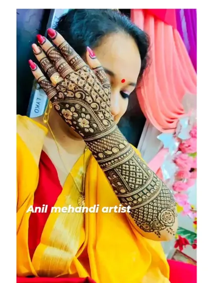 A client posing elegantly to show off her full-arm mehendi. The design is a beautiful mix of traditional bands and floral patterns.