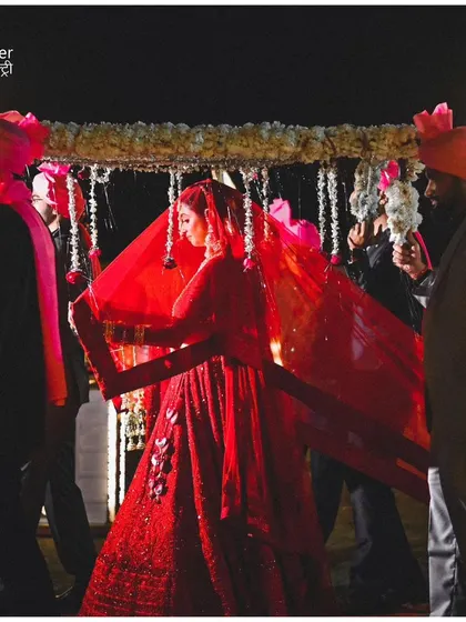 The bride's grand entrance, her red lehenga and veil creating a dramatic and beautiful image. We capture the full splendor of the bridal entry.