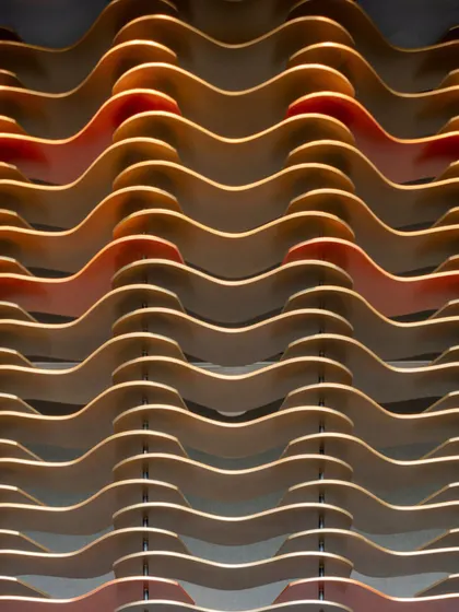 A close-up detail of the wavy, layered MDF plates of the Godrej South Estate facade. The interplay of contrasting colors and backlighting turns this architectural element into a work of art.