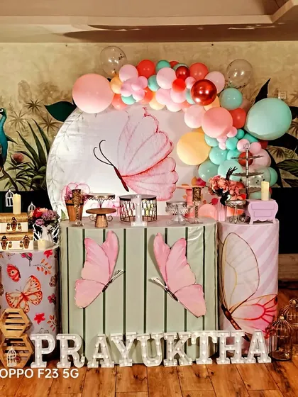 This elegant butterfly theme for Prayuktha's first birthday features a soft color palette and beautiful butterfly illustrations on the backdrop and pedestals. The organic balloon garland adds a touch of modern whimsy.