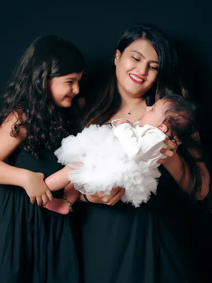 A tender moment between a mother, daughter, and the new baby. This image tells a story of growing love and the special bond between sisters.