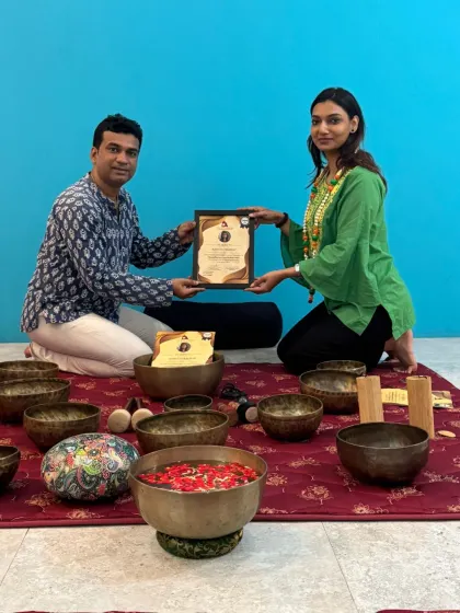 A student proudly accepts her Sound Healing certification, ready to embark on her journey as a sound therapist.