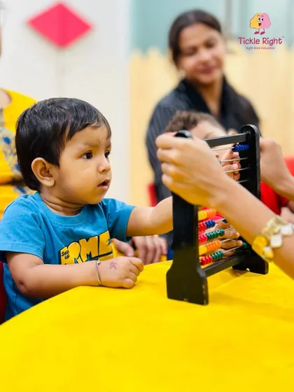 A young boy explores an abacus, a classic tool for learning mathematical concepts. We use a variety of tactile aids to make abstract ideas like numbers concrete and understandable.