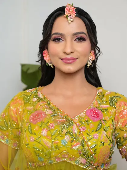 A beautiful portrait of the bride, smiling and confident. The makeup is fresh, fun, and perfect for a daytime event like Haldi or Mehendi.